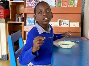 Deafblind boy working with pearls in Kenya